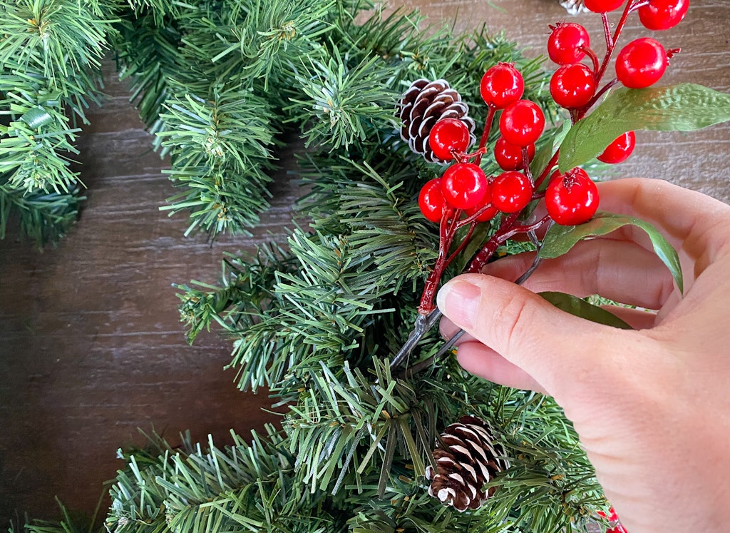 adding decorations to. a christmas wreath